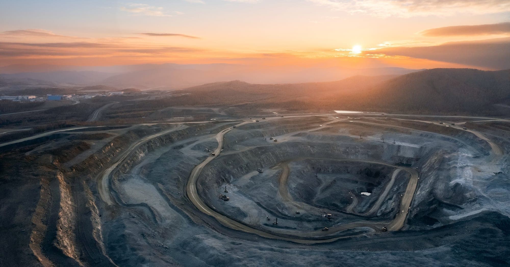 Open pit mine at sunset, haul roads spiralling to the bottom