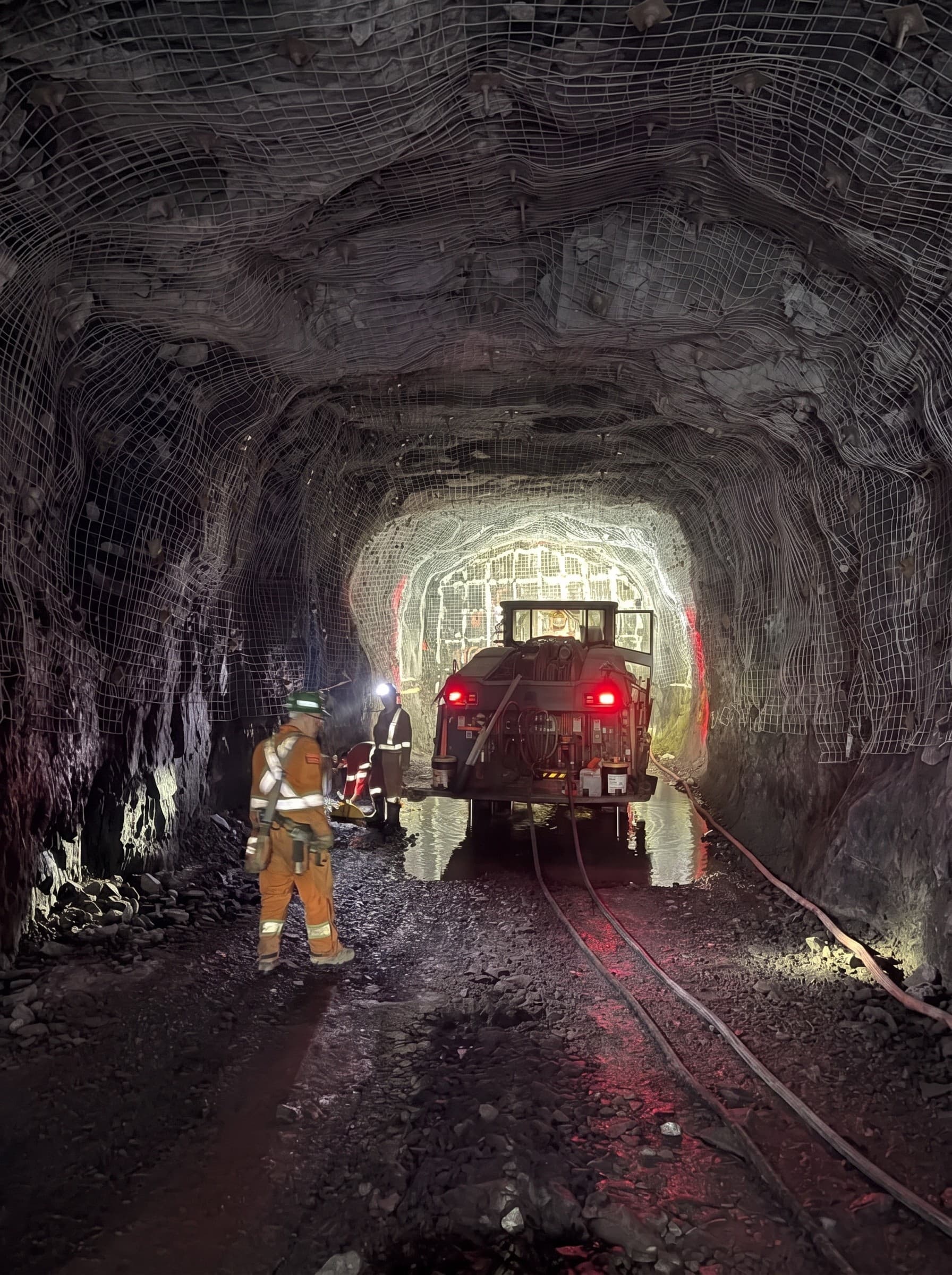 Crew working around a drill rig in an underground mine drift